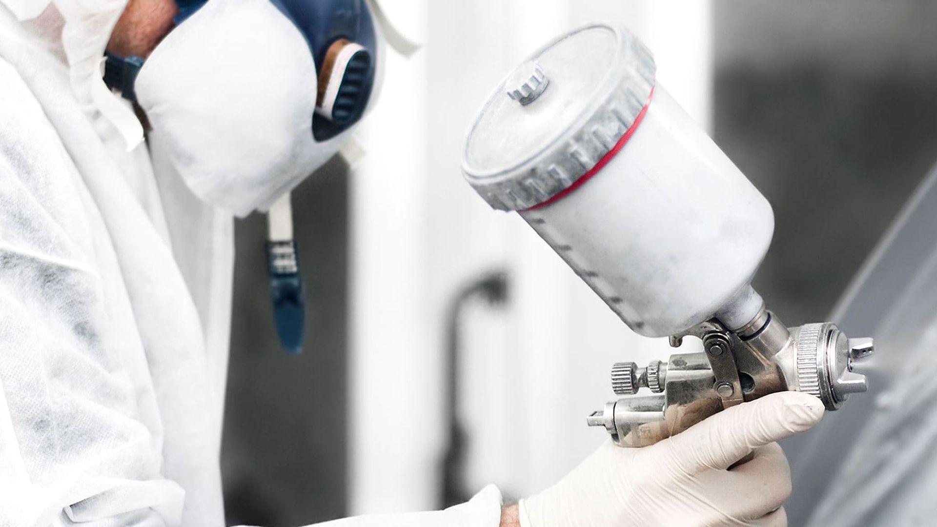 Mann in weißem Overall und einer hellen Sprühflasche in der Hand